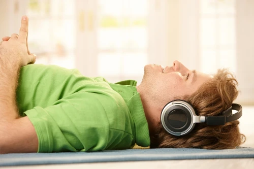 Man on his back, listening to music on his headphones